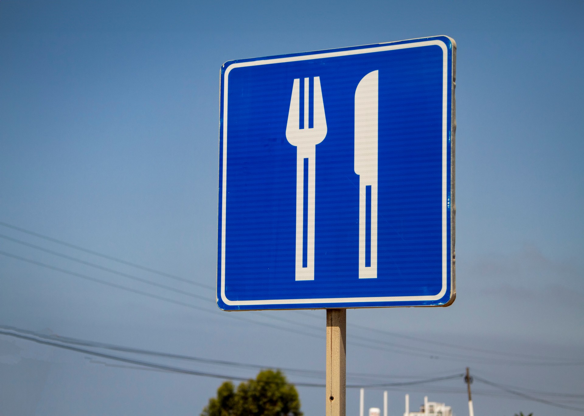 A blue road sign with a large white knife and fork in Rosarito Mexico